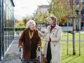 Opiekunka osób starszych z językiem angielskim wspiera starszą panią przy chodziku.