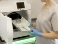 Osoba w rękawiczkach wkłada tacę z narzędziami do autoklawu. To ważny etap kursu sterylizacji medycznej.