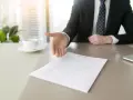 Biznesmen wyciąga rękę do uścisku nad dokumentem, symbolizującym rezygnację z pracy.