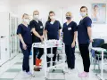 Pięć studentek pielęgniarstwa w granatowych uniformach i maseczkach stoi przy wózku medycznym. To ich przyszła praca dla studenta pielęgniarstwa.