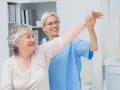 Pielęgniarka pomaga starszej pacjentce w ćwiczeniach rehabilitacyjnych. To część kursu leczenia ran.