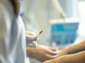 Ręka w rękawiczce trzyma igłę do karmienia pozajelitowego w domu.