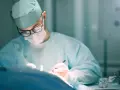 Chirurg w okularach i masce, w czepku i fartuchu, wykonuje precyzyjną specjalizację chirurgiczną.