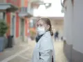 Kobieta w masce na twarzy, zastanawia się, ile można być na L4, spacerując ulicą.