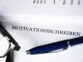 Okulary i długopis leżą obok dokumentu z napisem "MOTIVATIONSSCHREIBEN".