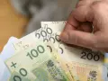 Dłoń trzyma banknoty 100 i 200 zł. Czy to już zapowiedź podwyżki najniższej krajowej 2026?