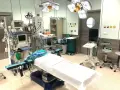 Sala operacyjna gotowa do zabiegu. Pielęgniarka instrumentariuszka przygotowała sprzęt: aparat do znieczulenia, stoły, lampy.