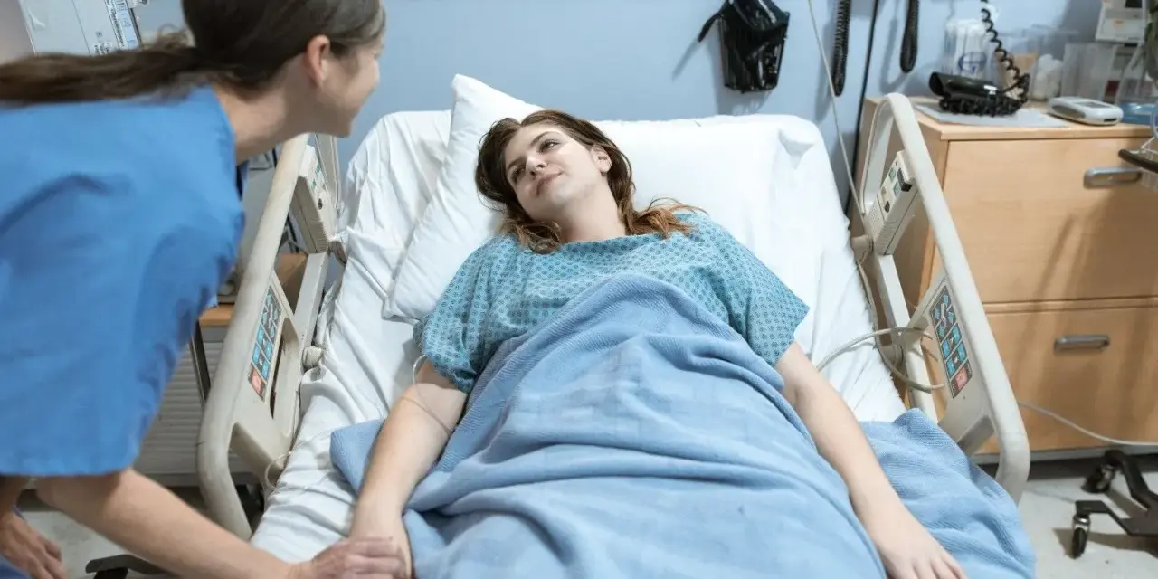 Pielęgniarka trzyma za rękę pacjentkę w szpitalnym łóżku. To jak list motywacyjny dla zdrowia, pełen nadziei.