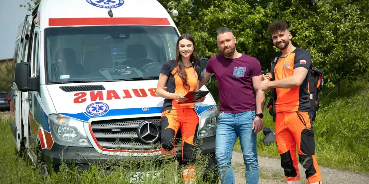 Trzech ratowników medycznych stoi obok karetki. Zastanawiasz się, ile godzin pracuje ratownik medyczny?