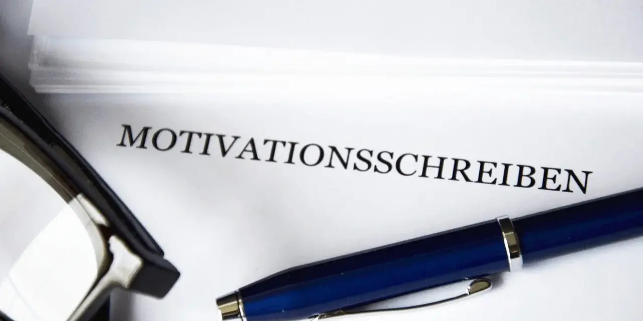 Okulary i długopis leżą obok dokumentu z napisem "MOTIVATIONSSCHREIBEN".