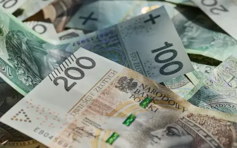 Złotówki, w tym banknot 200 zł, tworzą stos. Marzenia o wakacjach w 2026 roku? Trzynastka pomoże!
