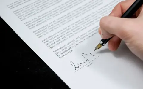 Podpisanie aneksu do umowy. Dłoń z piórem wiecznym składa podpis na dokumencie.