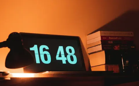 Na ekranie laptopa 16:48. Obok stos książek, w tym "#socialholic". Ile przerwy na 12 godzin pracy?