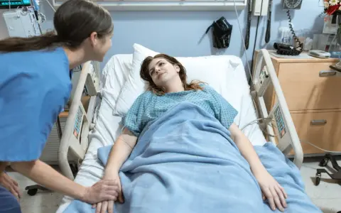 Pielęgniarka trzyma za rękę pacjentkę w szpitalnym łóżku. To jak list motywacyjny dla zdrowia, pełen nadziei.