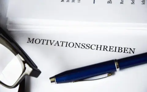 Okulary i długopis leżą obok dokumentu z napisem "MOTIVATIONSSCHREIBEN".