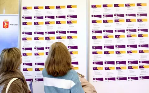 Dwie kobiety przeglądają tablicę z ofertami pracy, szukając rozwiązań problemu bezrobocia w Polsce.