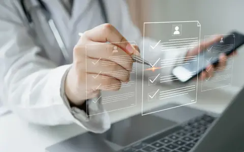 Lekarz w białym kitlu analizuje dokumenty na ekranie, w tym potencjalne zwolnienie lekarskie od psychiatry płatne 100%.