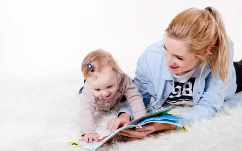Uśmiechnięta opiekunka czyta książeczkę dziecku. To idealny przykład, jak wygląda praktyka na kursie opiekuna w żłobku.