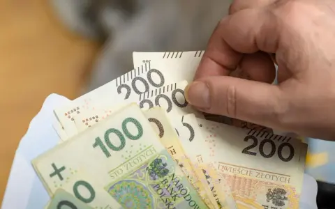 Dłoń trzyma banknoty 100 i 200 zł. Czy to już zapowiedź podwyżki najniższej krajowej 2026?