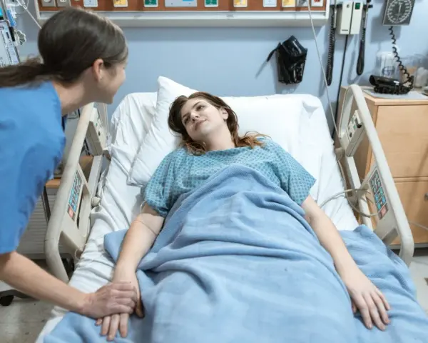 Pielęgniarka trzyma za rękę pacjentkę w szpitalnym łóżku. To jak list motywacyjny dla zdrowia, pełen nadziei.