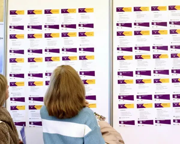 Dwie kobiety przeglądają tablicę z ofertami pracy, szukając rozwiązań problemu bezrobocia w Polsce.