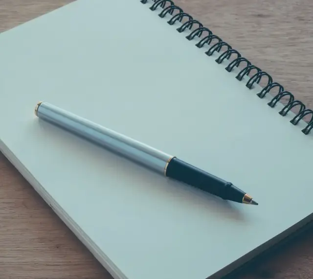 Notes for a podanie o praktyki. Notatnik i długopis na drewnianym blacie.