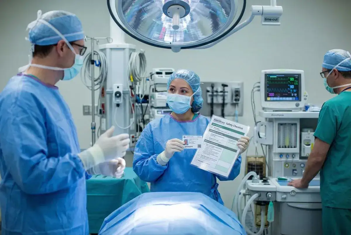 Zespół medyczny w sali operacyjnej omawia procedury. Kobieta trzyma listę kontrolną bezpieczeństwa, podkreślając znaczenie precyzji w specjalizacji operacyjnej.