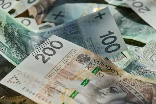 Złotówki, w tym banknot 200 zł, tworzą stos. Marzenia o wakacjach w 2026 roku? Trzynastka pomoże!